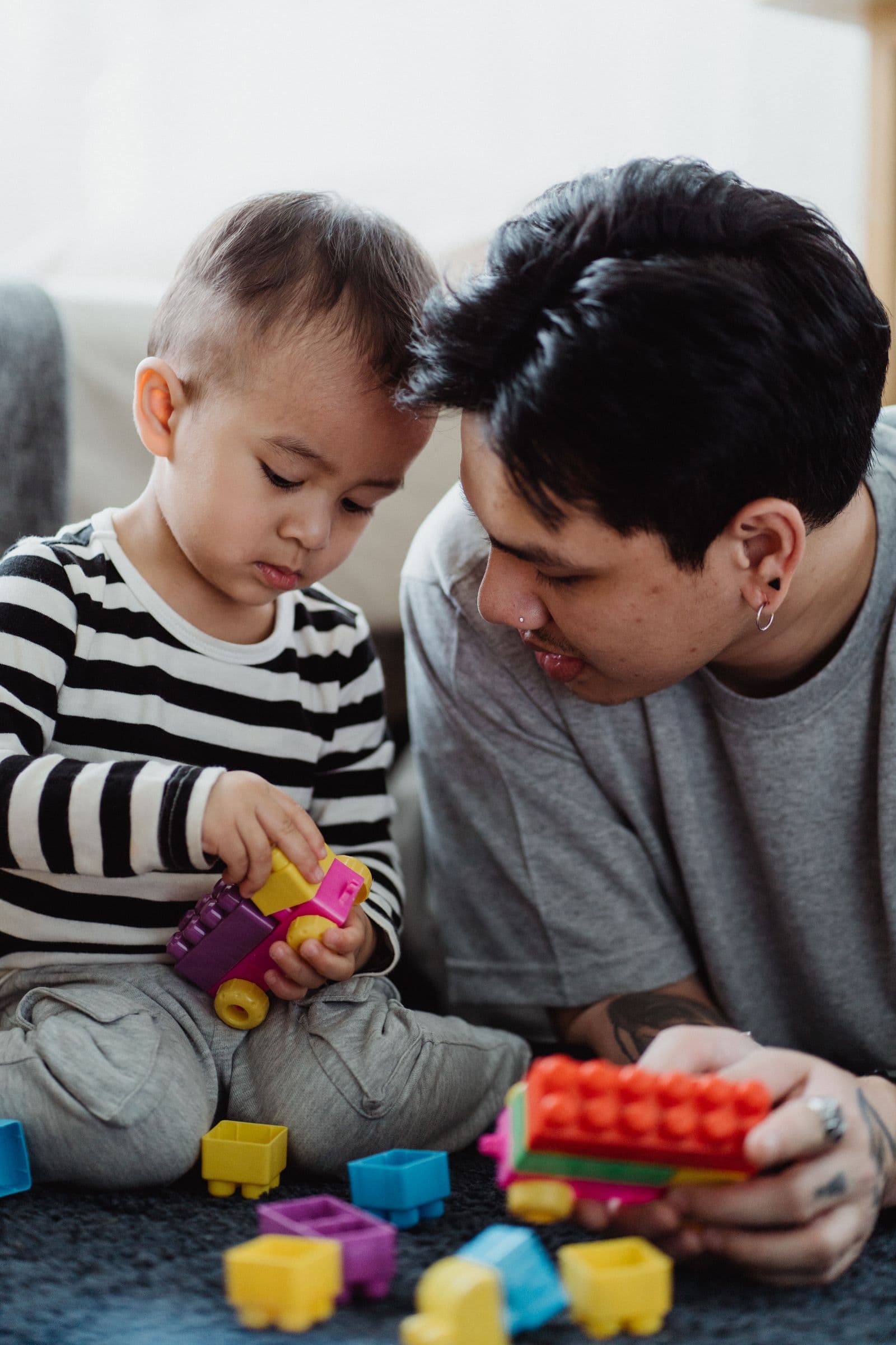 A dad building colourful blocks with his toddler son