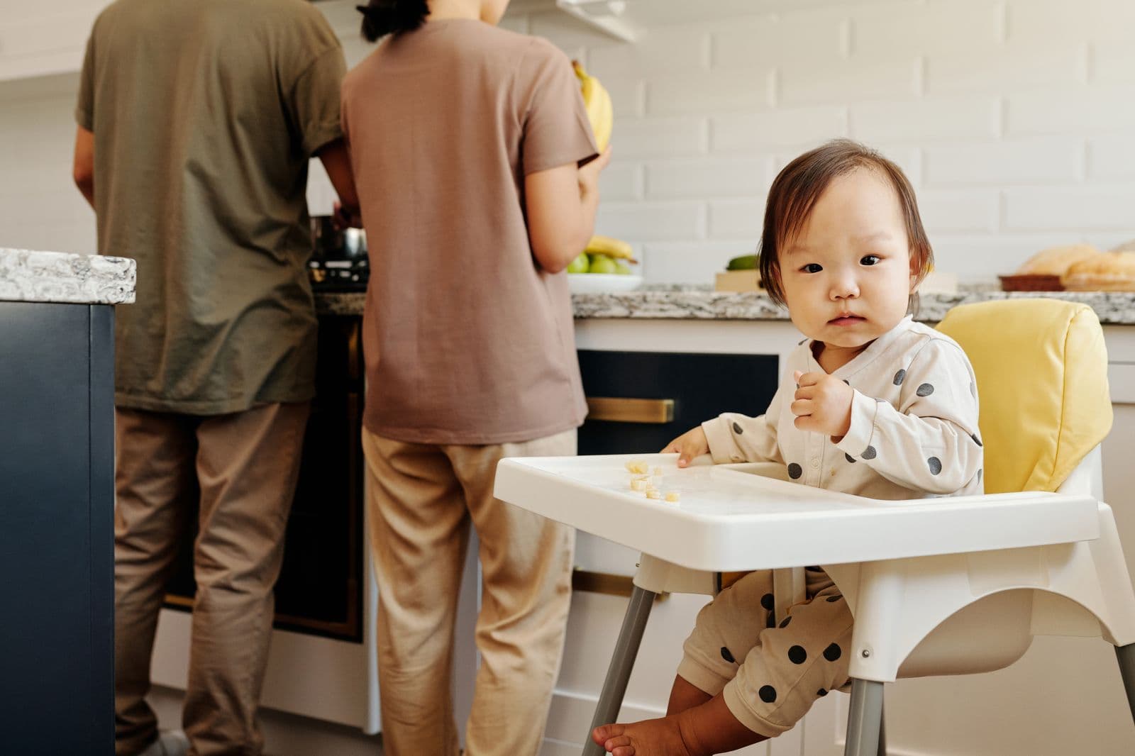 A toddler in a high chair while parents cook