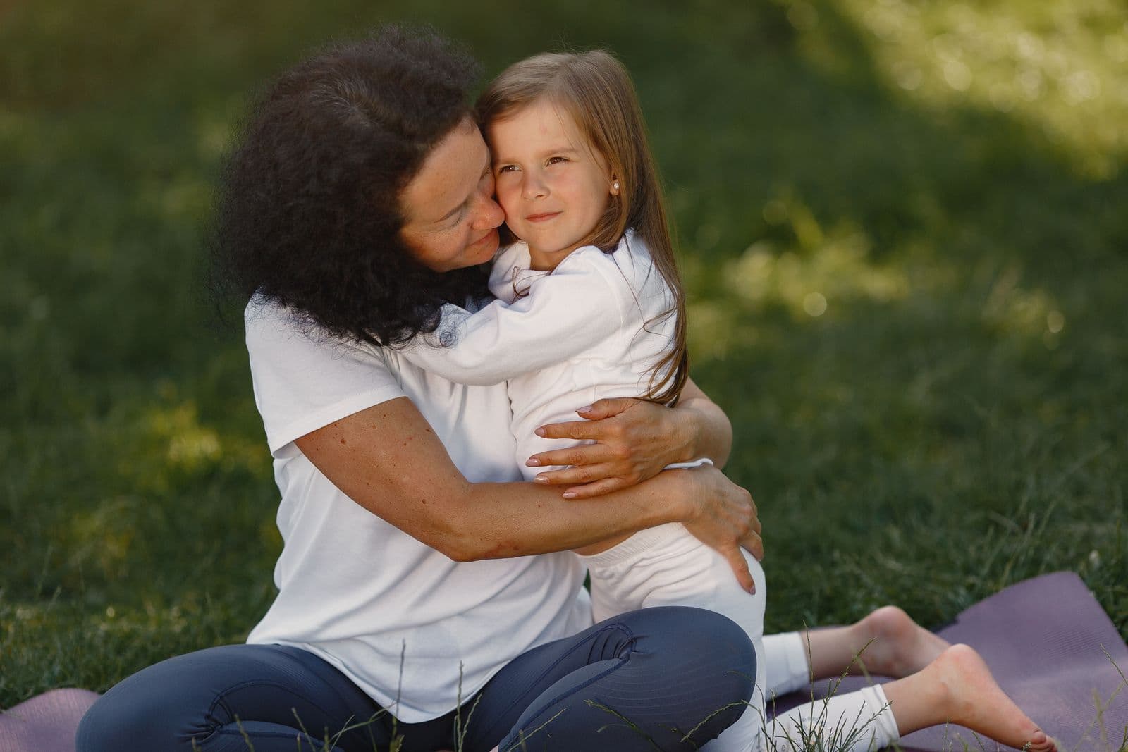 A little girl hugging her mum on the grass