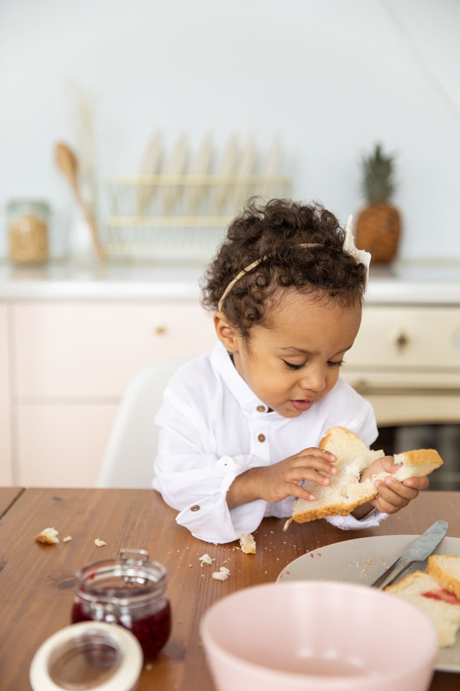 A toddler eating bread with jam