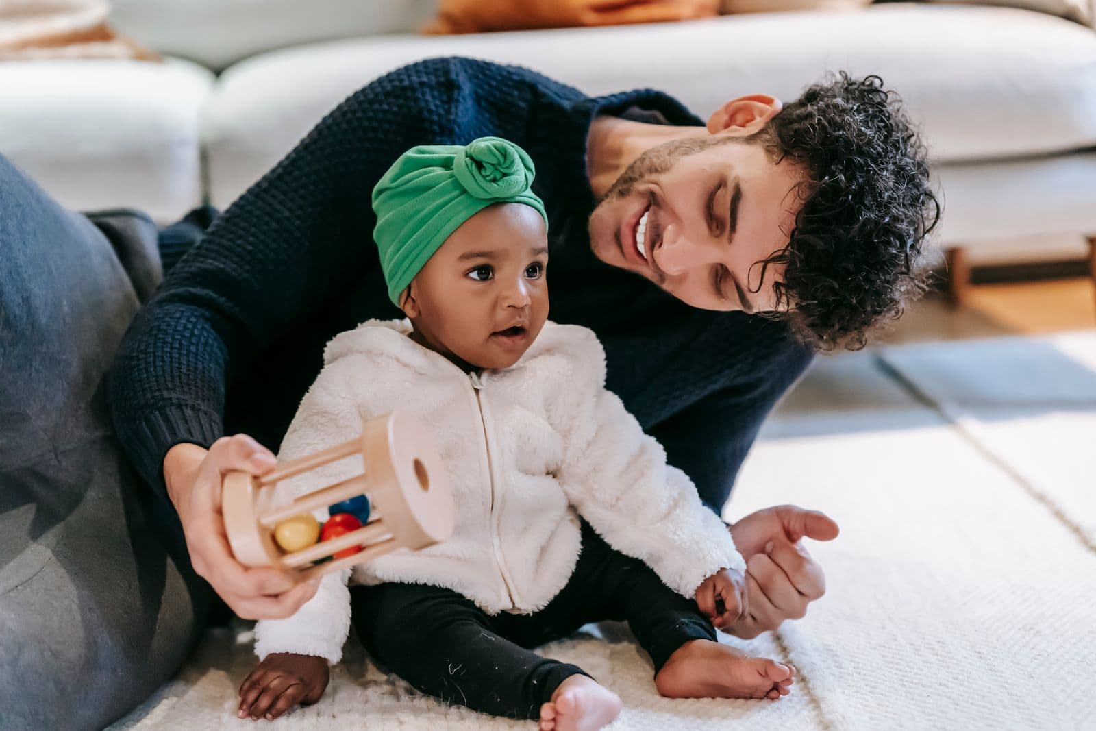 A smiling father lying on the carpet with his baby girl